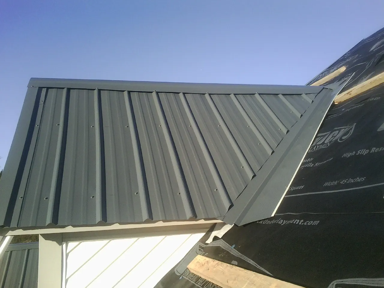 Gray metal roof panels going on over a garage gable in Oldtown