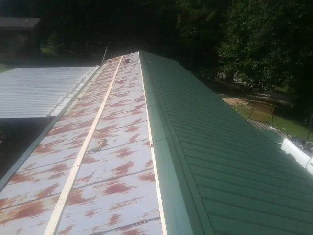 Old rusted panels beside newly installed green metal roofing — Wind Damage Roof Repair by Roofing Brothers in Oldtown