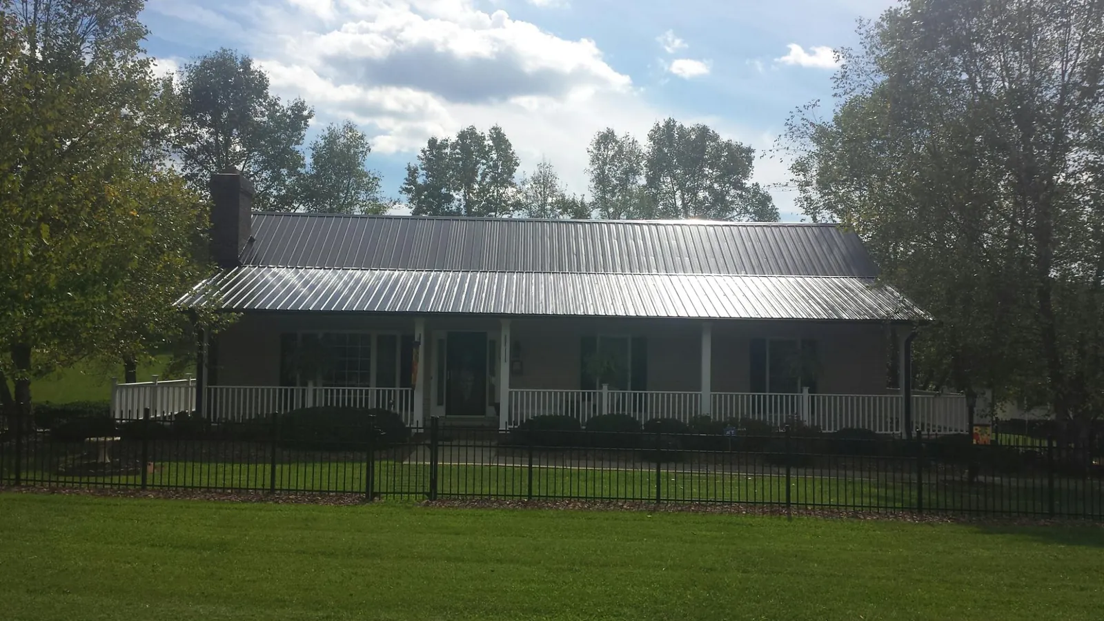 Gray metal roof on a brick ranch with a full width front porch — Gutter Guard Installation work by our crew in Oldtown