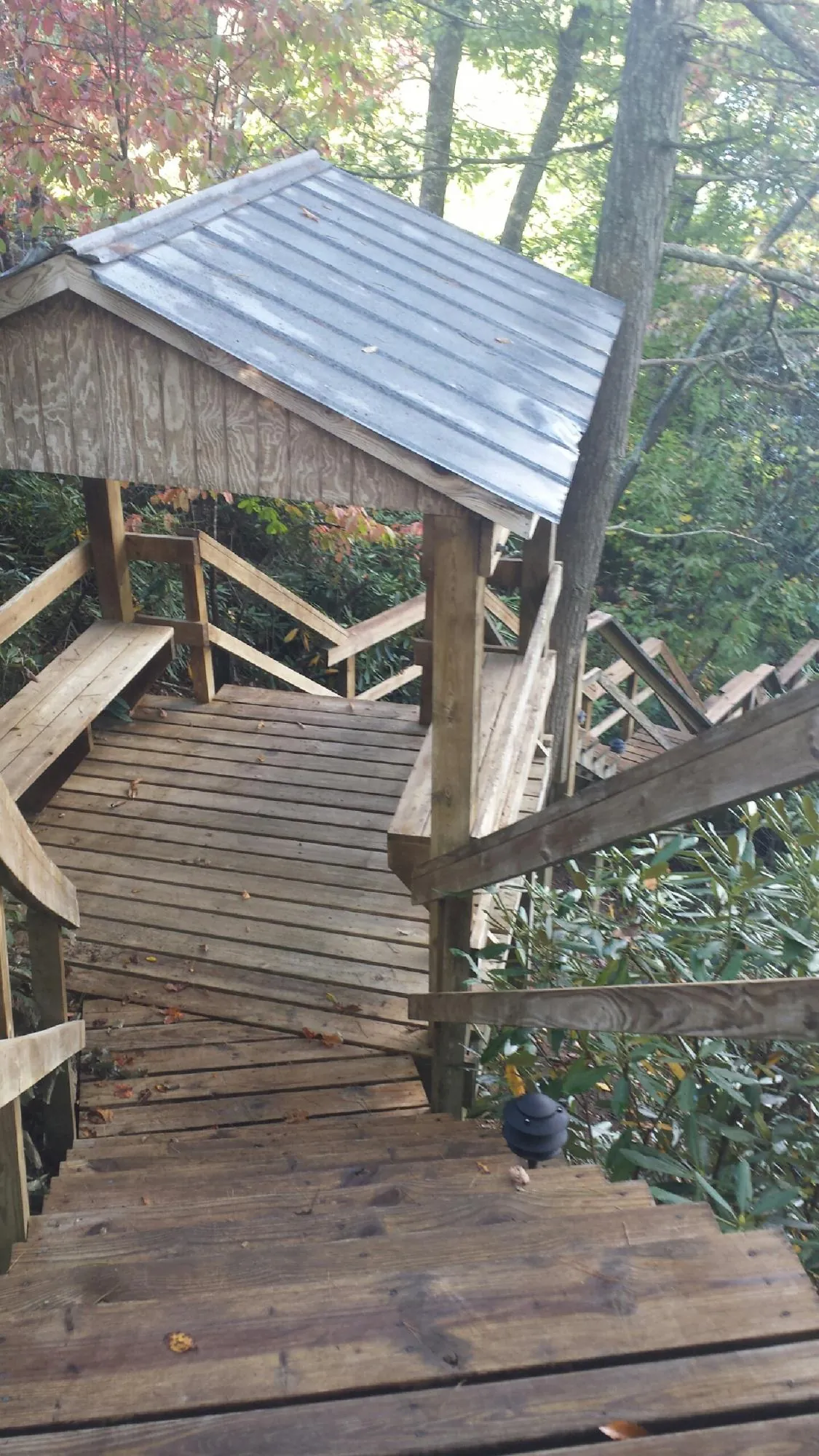 Metal roofed shelter over wooden steps on a wooded walkway — Skylight Repair & Installation work by our crew in Oldtown