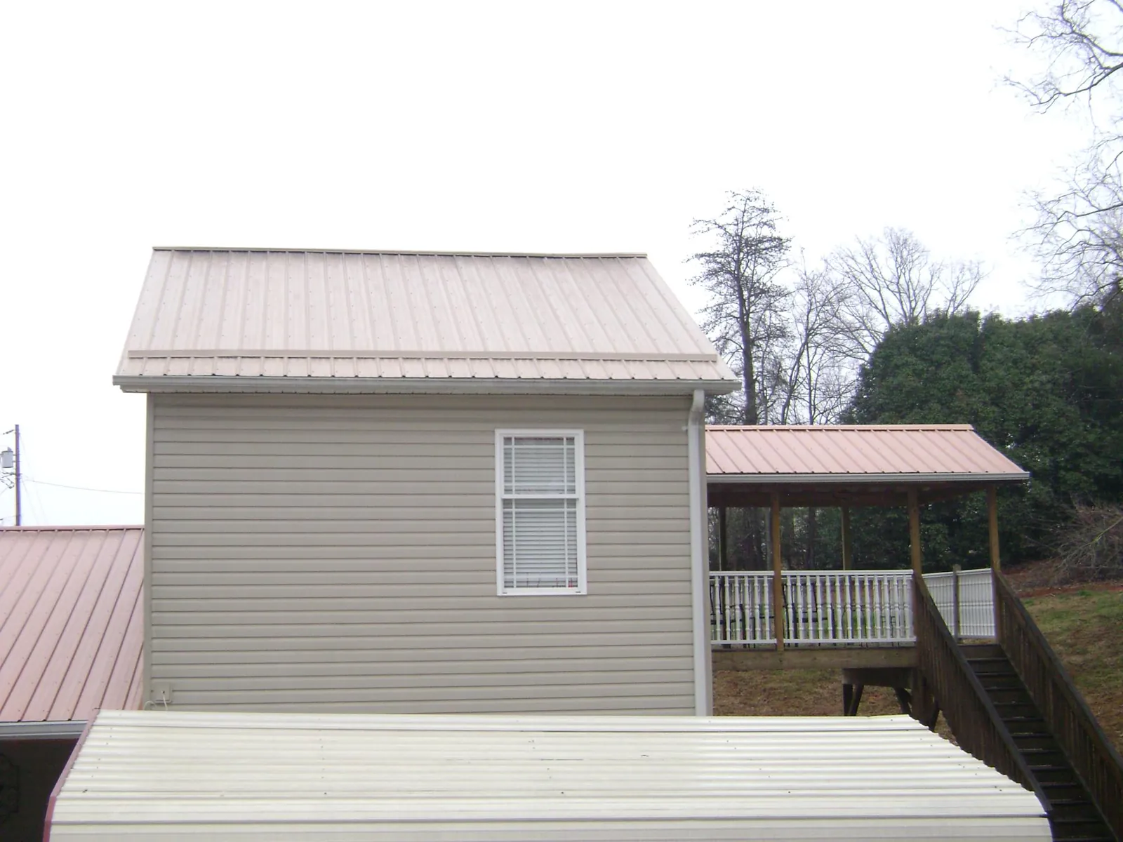 Tan metal roofs on a two story addition and attached porch, from a Roof Replacement job in Oldtown